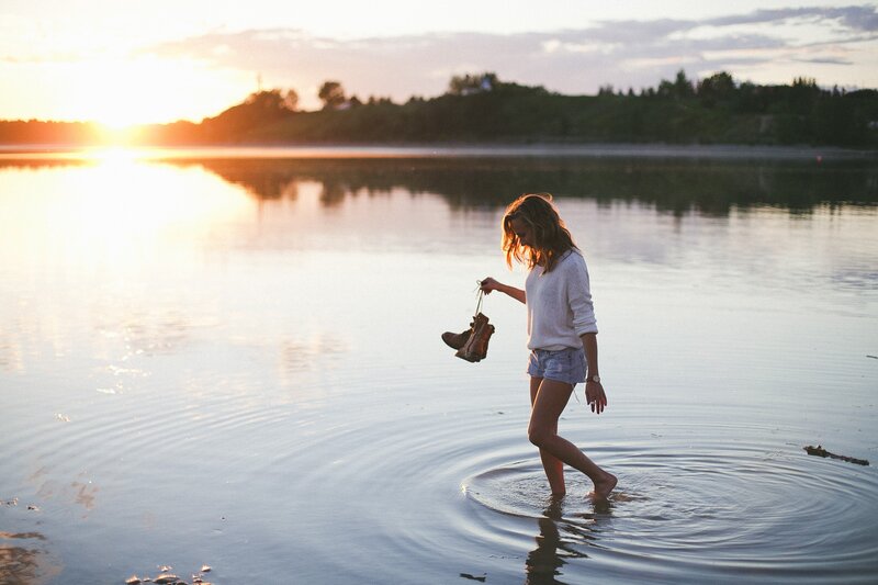 Woman walking in water at sunset