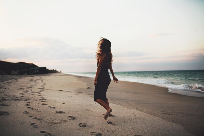woman walking on beach at sunset