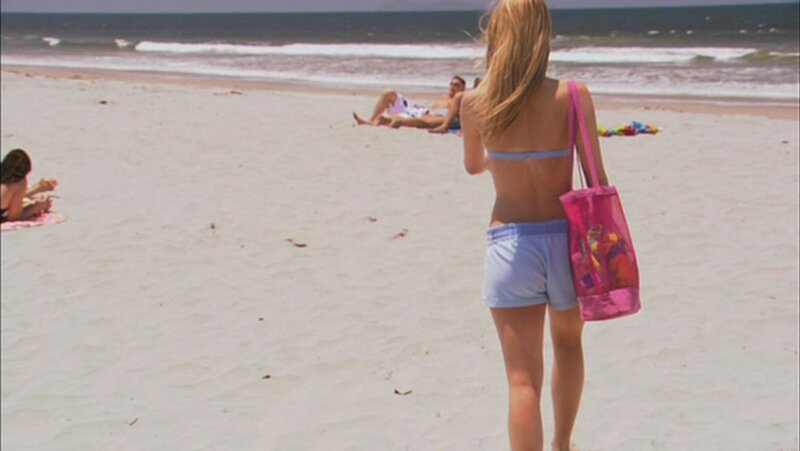 Woman walking on beach with bag