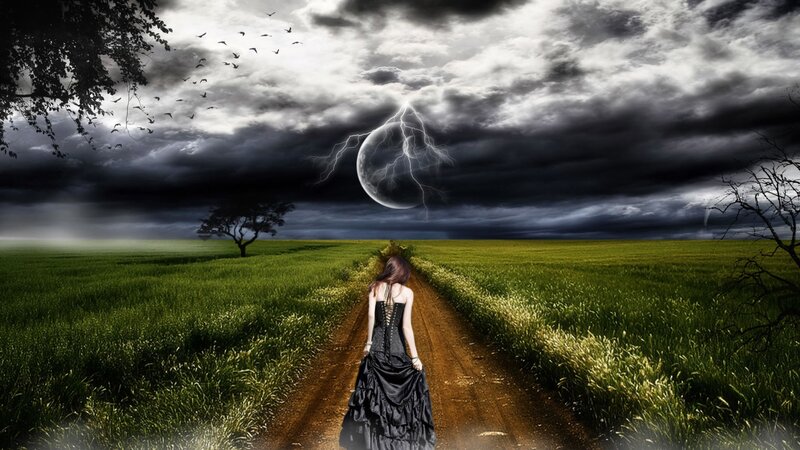 Woman walking on path under stormy sky