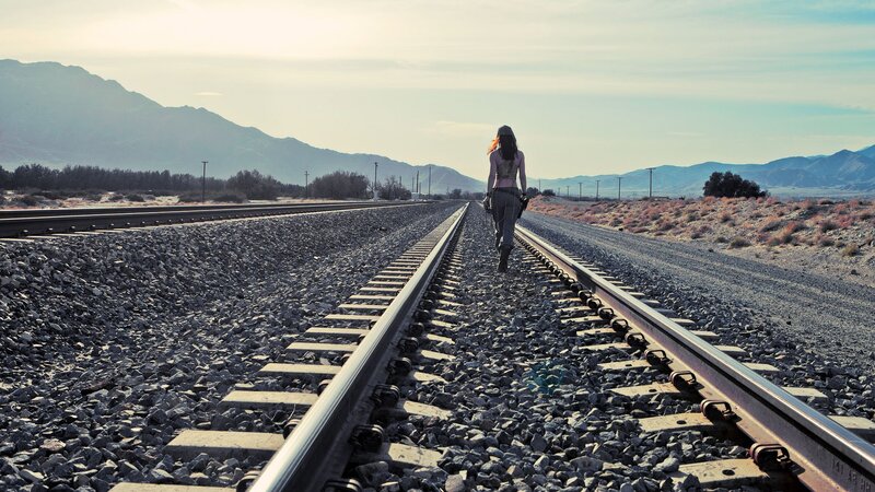 Woman Walking on Train Tracks — Gray