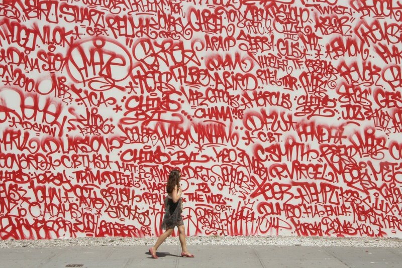 woman walking past graffiti wall