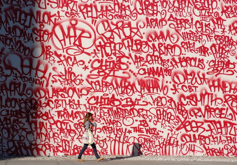 woman walking past graffiti wall