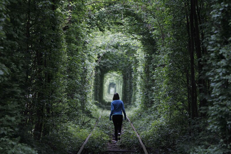 woman walking through green tunnel