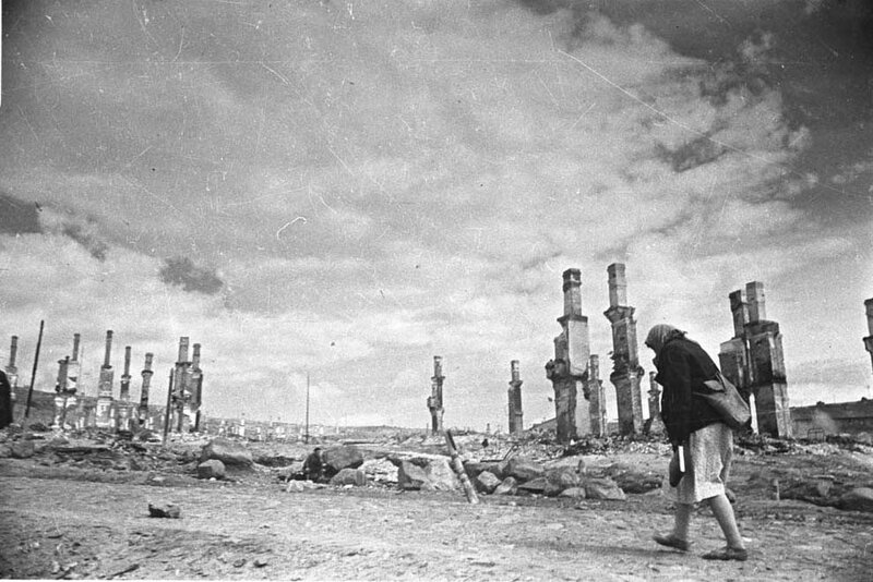 Woman walks through war ruins