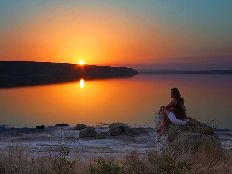 Woman watching sunset by the lake