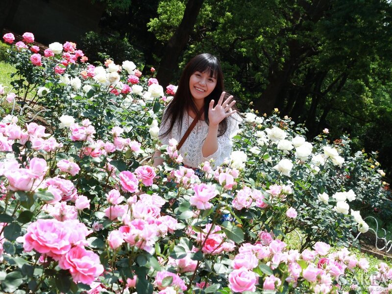 Woman waving in rose garden