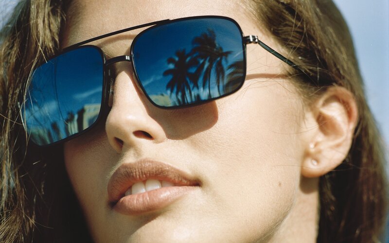 woman wearing sunglasses with palm tree reflection
