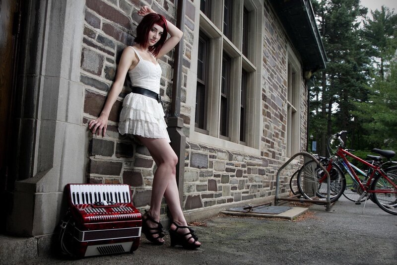 Woman with accordion by stone building