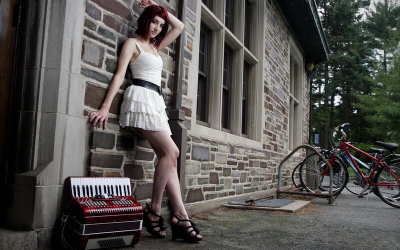 Woman with accordion by stone building