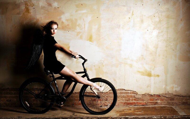 woman with angel wings on bicycle
