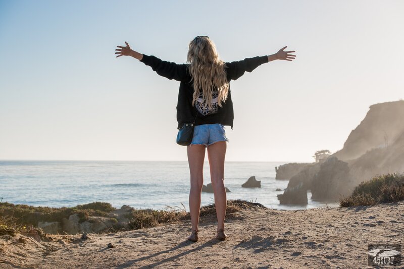 woman with arms outstretched at beach