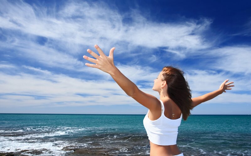 Woman with arms outstretched at beach