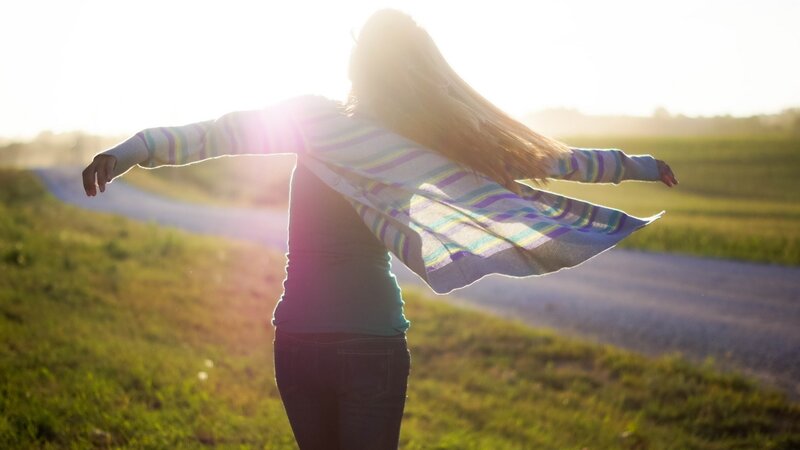 woman with arms outstretched at sunset