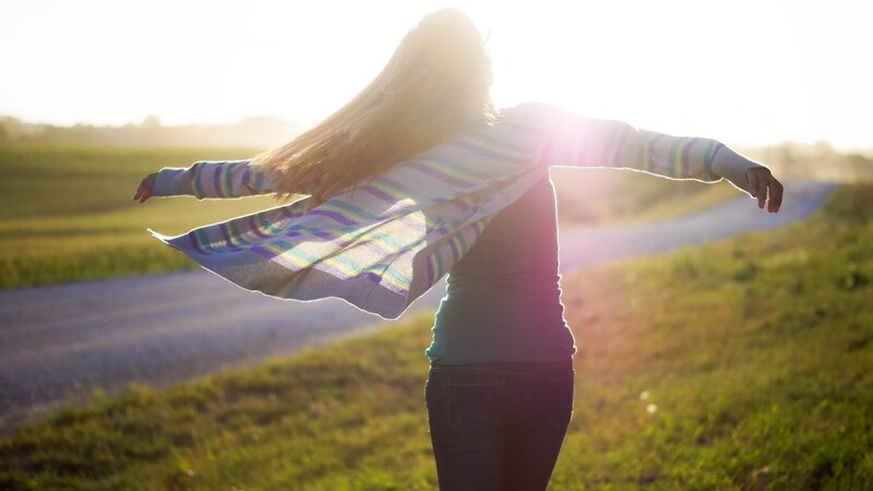 woman with arms outstretched in field