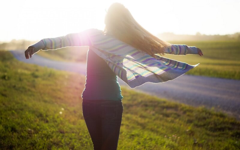 woman with arms outstretched in field