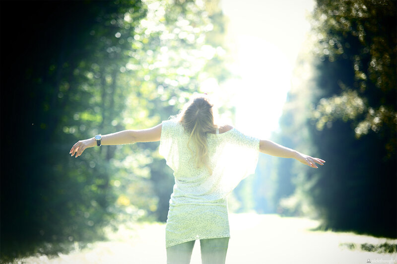 woman with arms outstretched in sunlight