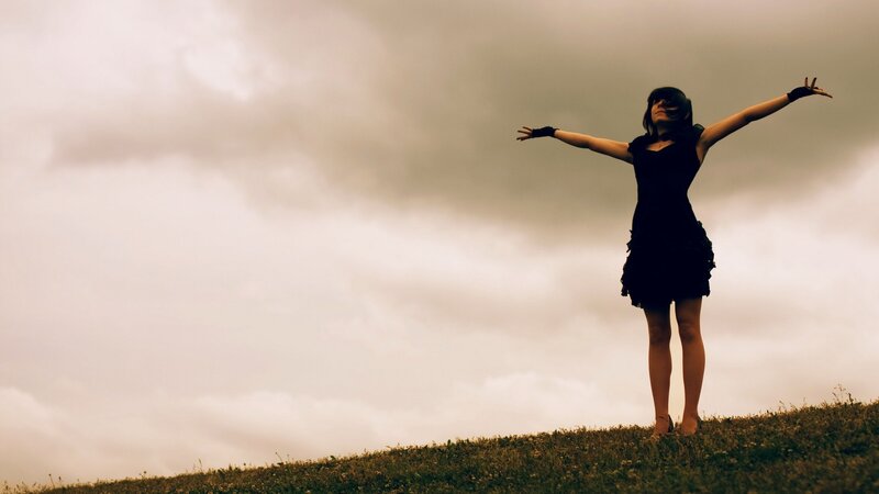 woman with arms outstretched on hill