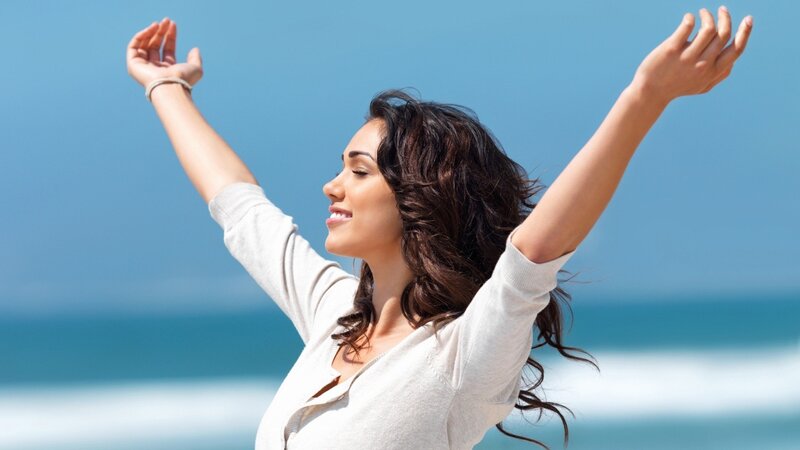 woman with arms raised at beach