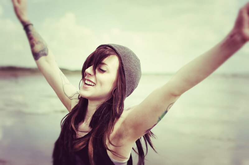 woman with arms raised at beach