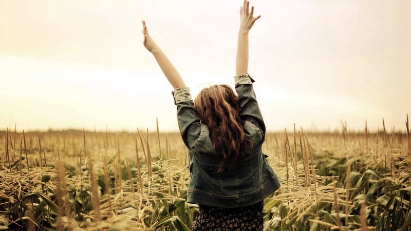 woman with arms raised in field