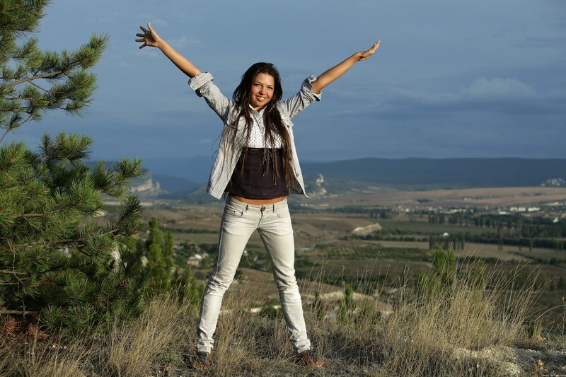 Woman with arms raised on hill