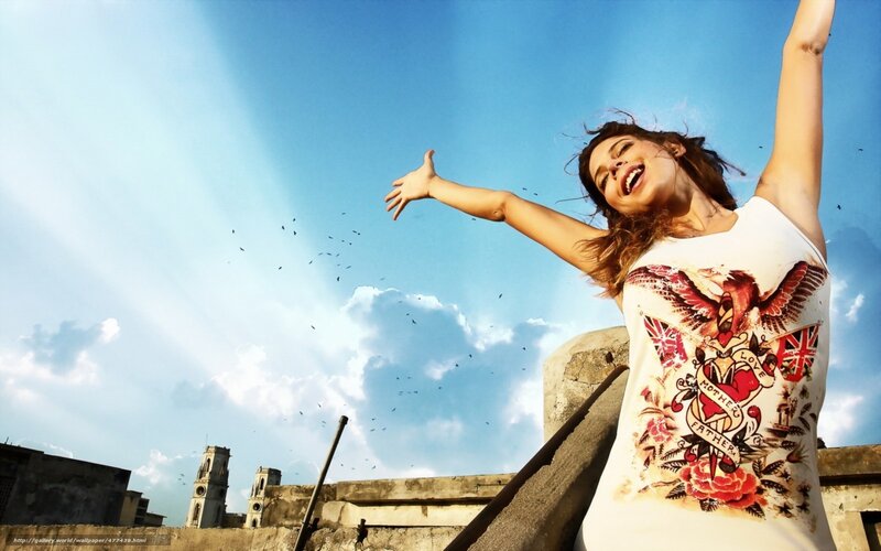woman with arms raised on rooftop