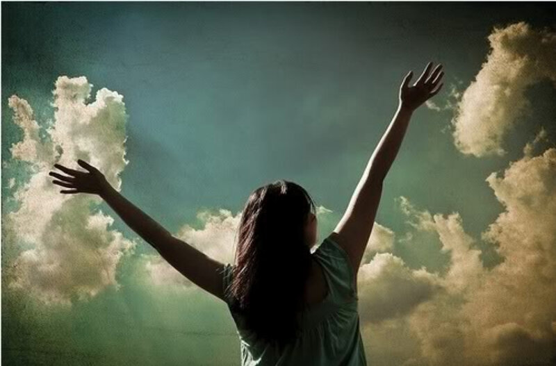 woman with arms raised to sky