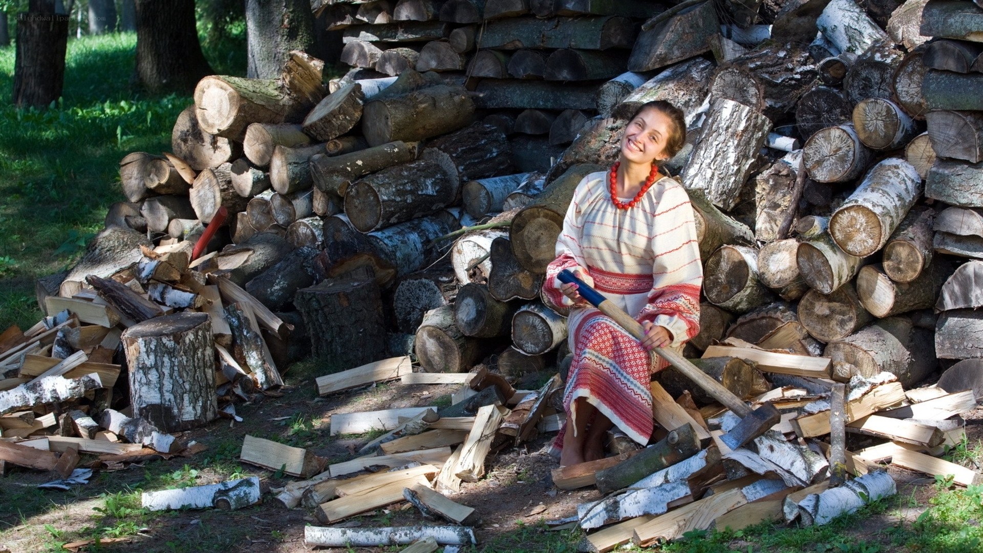 Woman with axe by firewood pile