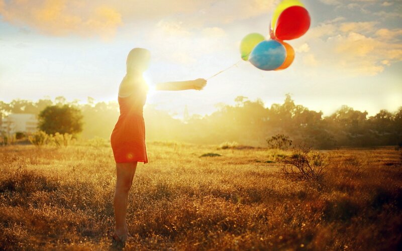 Woman with balloons in field