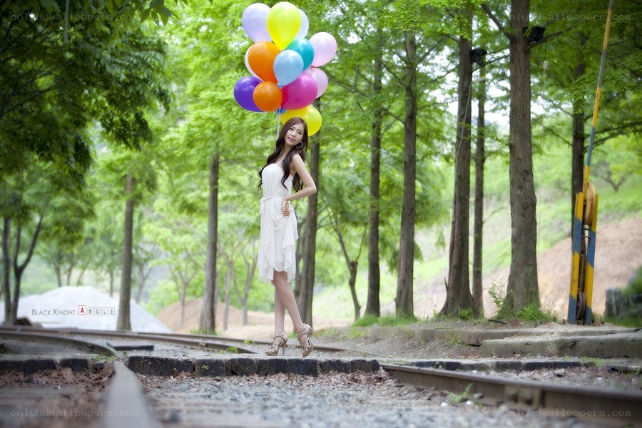 Woman with balloons on train tracks