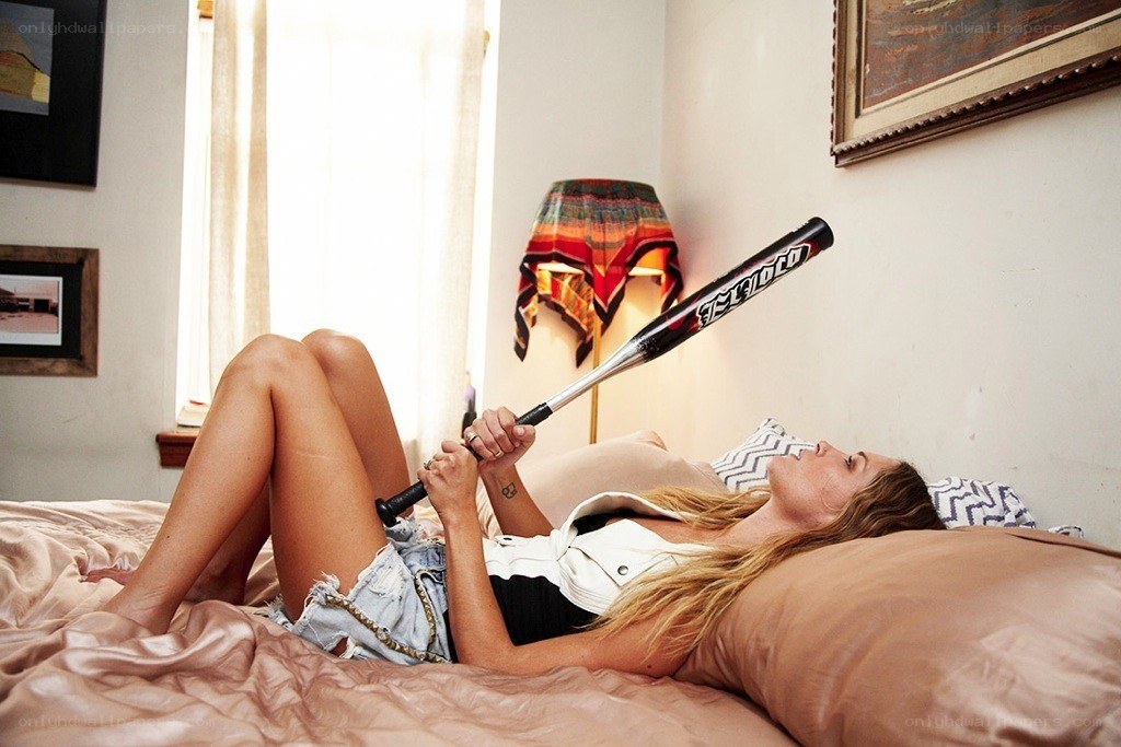 Woman with baseball bat on bed