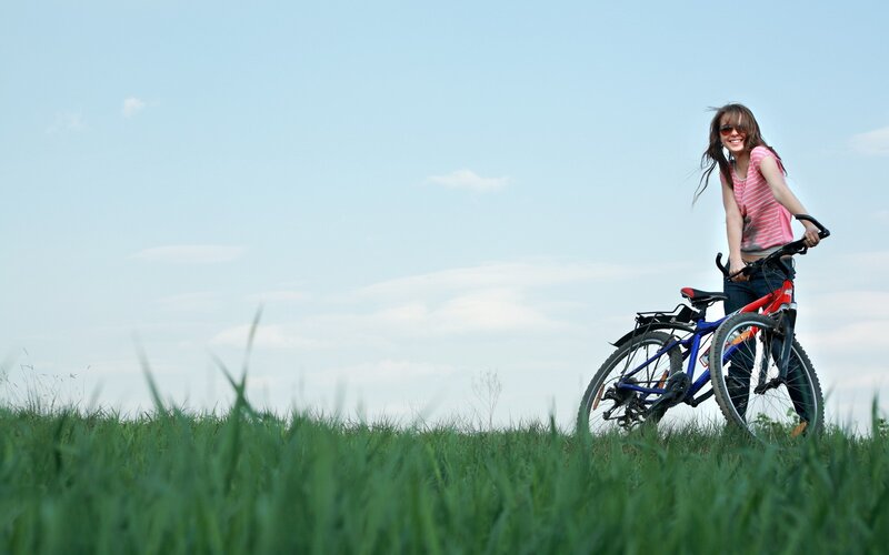 Woman with bicycle in field