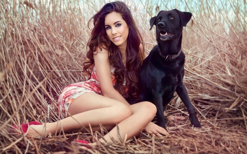 woman with black dog in field