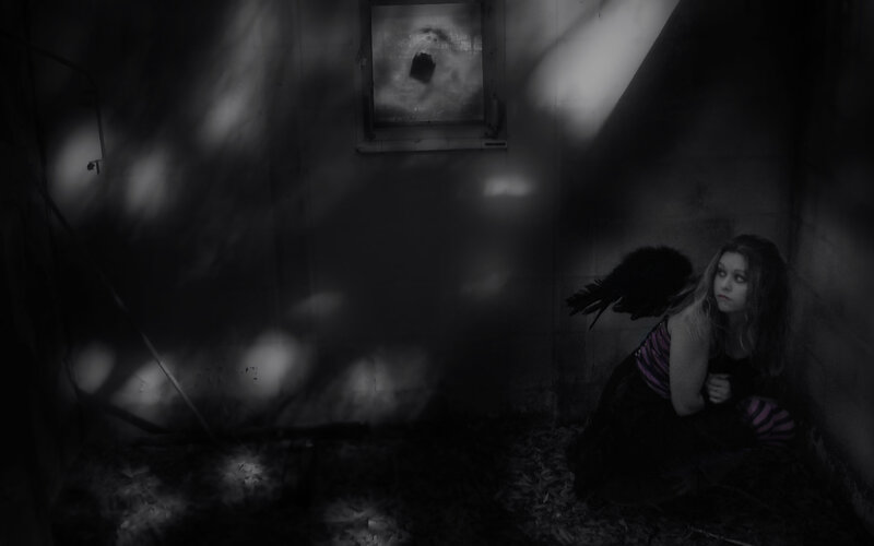 woman with black wings in dark room