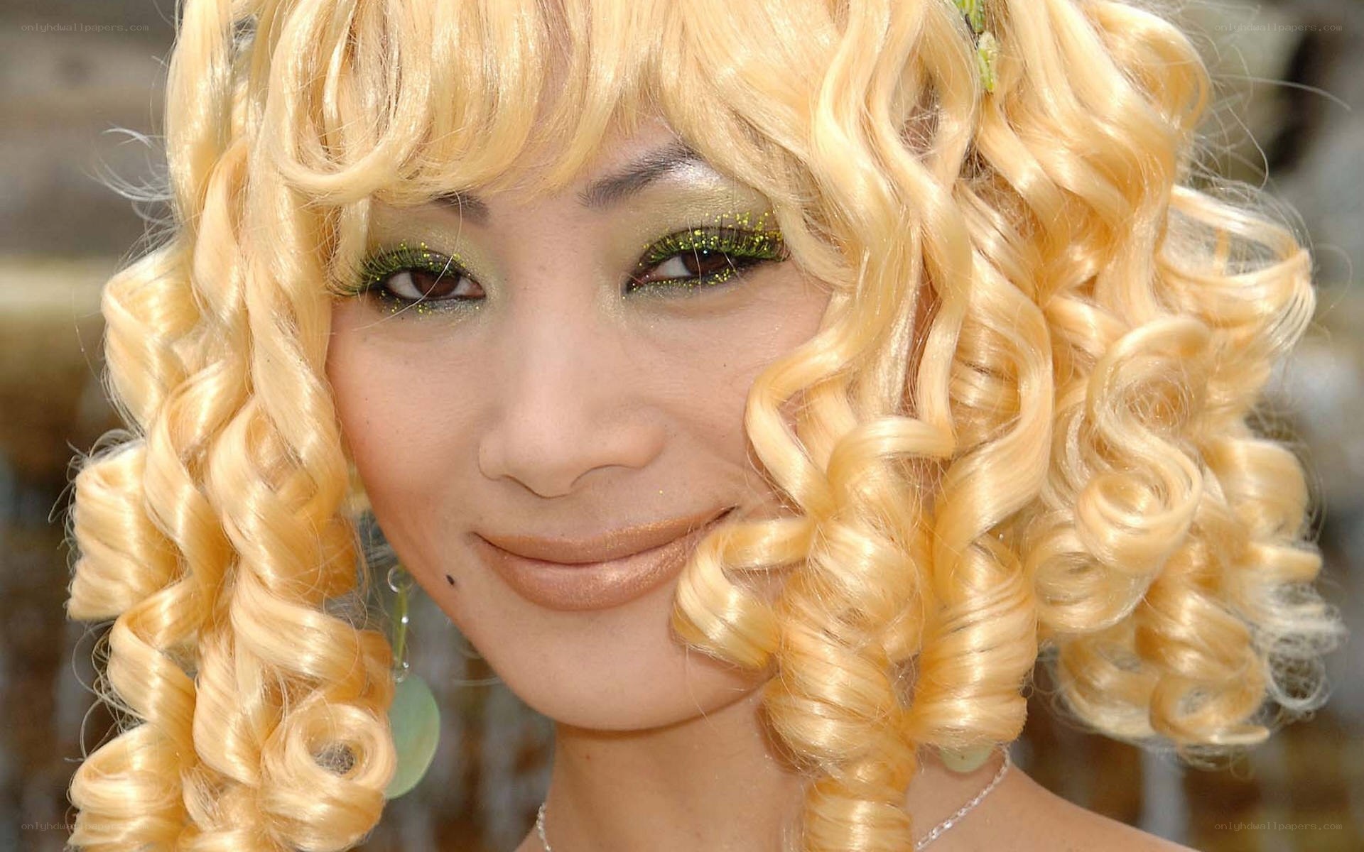 woman with blonde curls and green makeup
