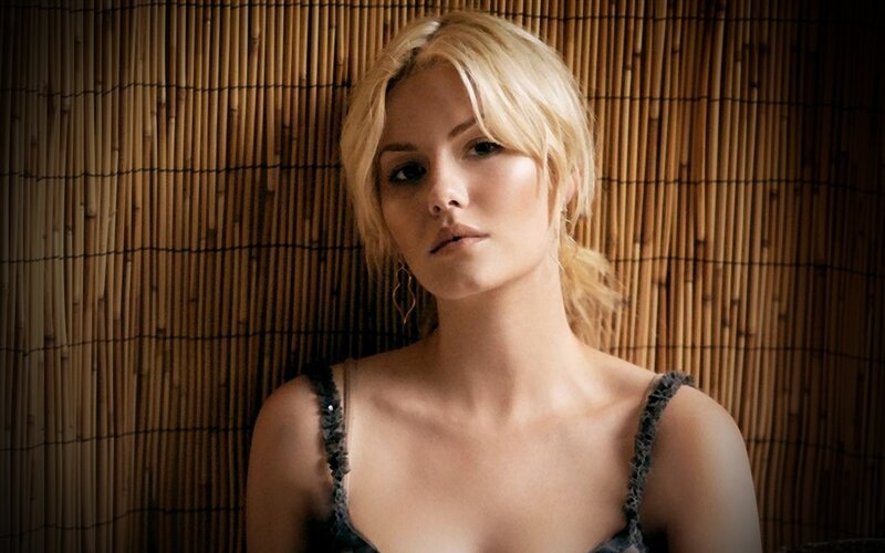 woman with blonde hair against bamboo wall