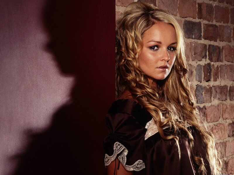 woman with blonde hair against brick wall