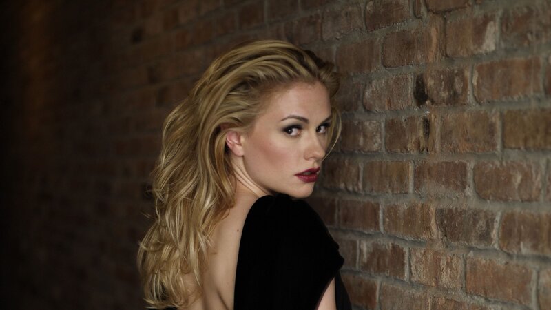 woman with blonde hair against brick wall
