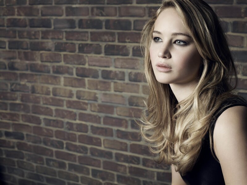 woman with blonde hair against brick wall