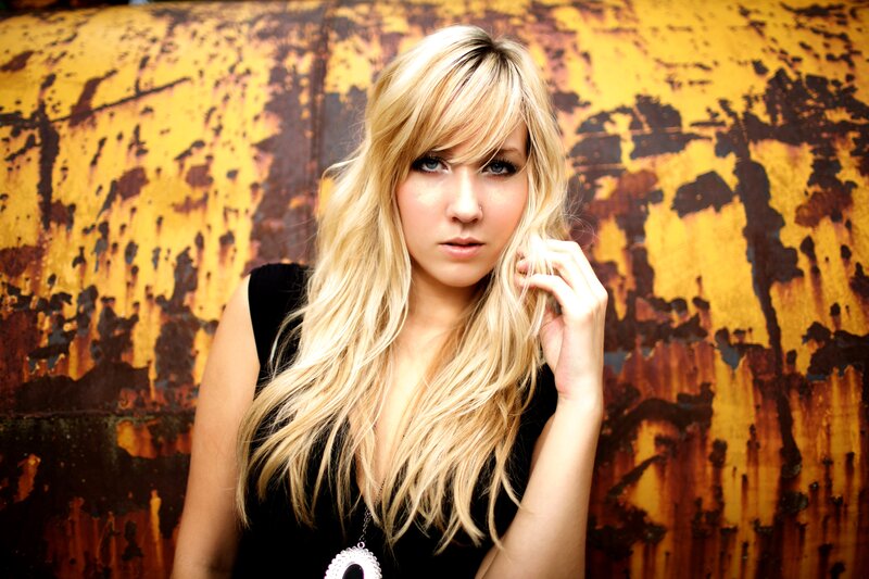 woman with blonde hair against rusted wall