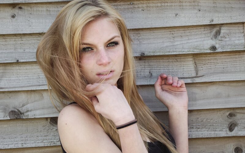 woman with blonde hair against wood