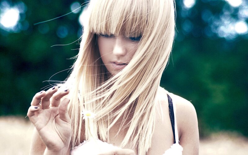 woman with blonde hair holding daisy