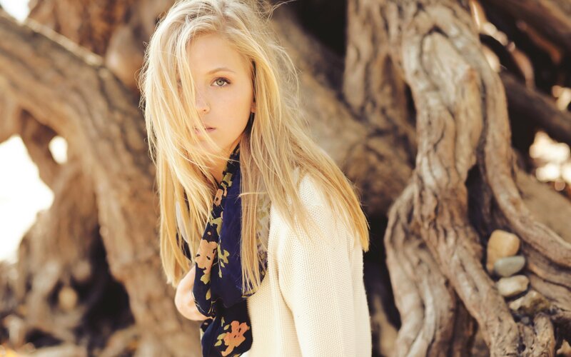 woman with blonde hair in front of tree roots