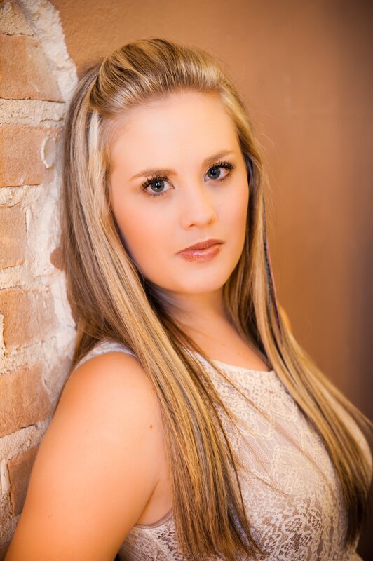 woman with blonde hair leaning against brick wall