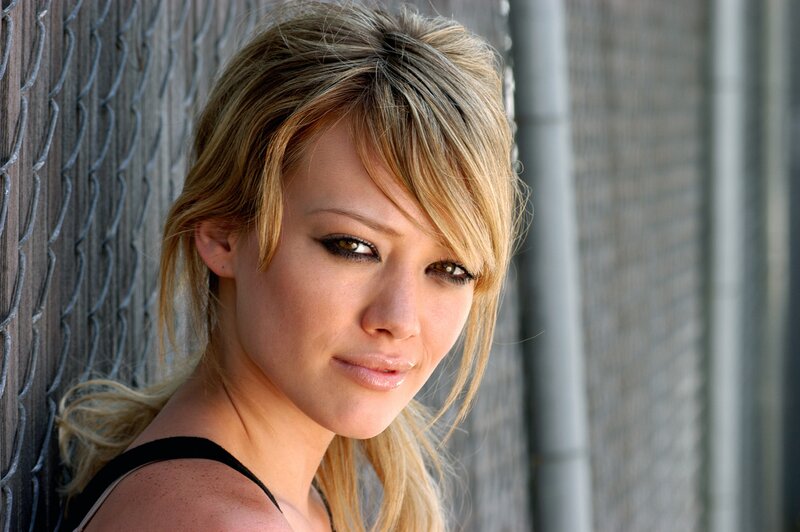 woman with blonde hair leaning against fence