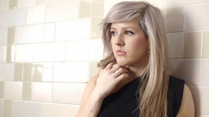 woman with blonde hair leaning against wall