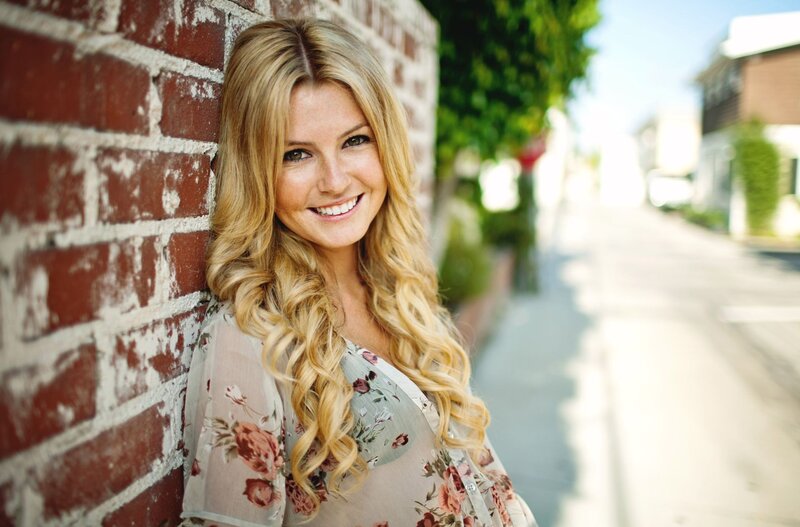 woman with blonde hair leaning on brick wall