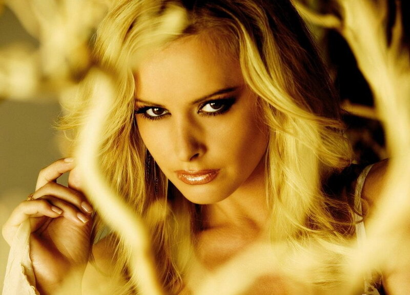 woman with blonde hair looking through branches