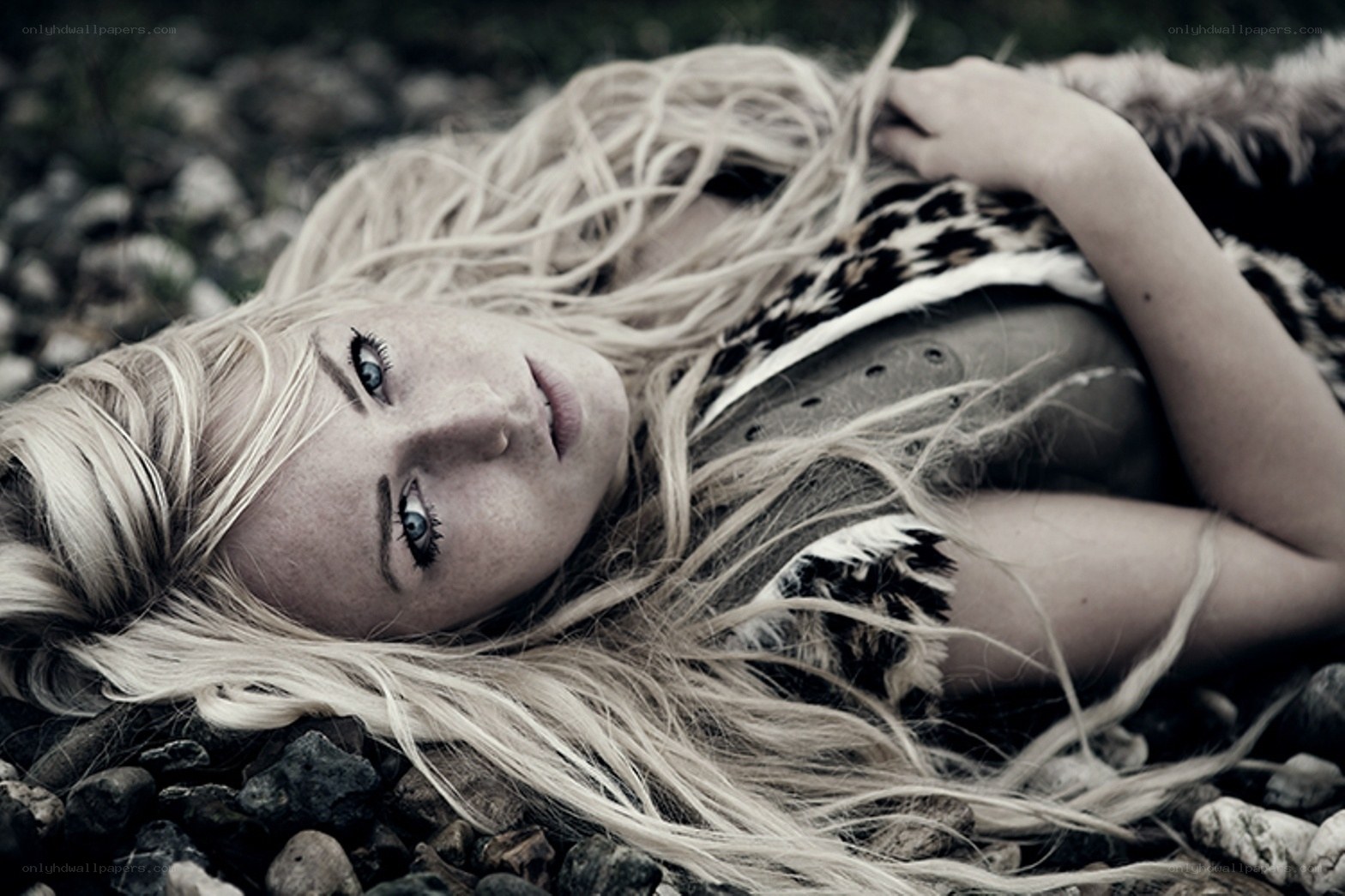 woman with blonde hair lying on rocks